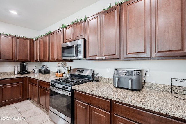 kitchen featuring light tile patterned flooring, light stone countertops, and appliances with stainless steel finishes