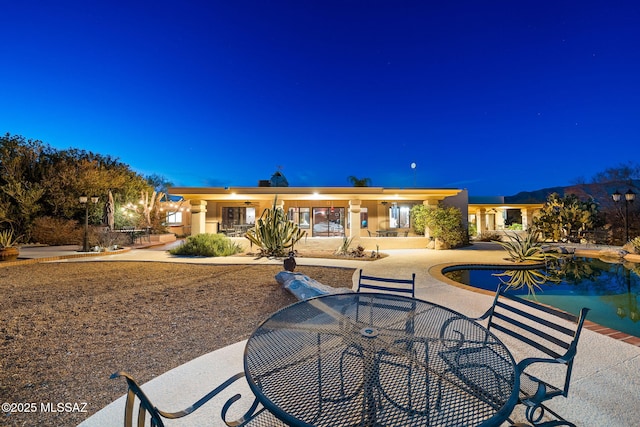 back house at night featuring a patio