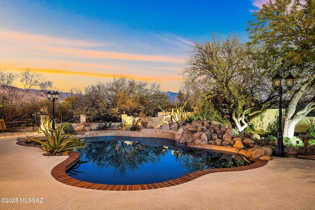 pool at dusk with a patio