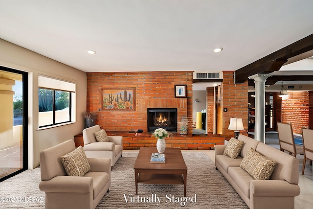 living room with decorative columns, brick wall, and a fireplace