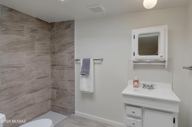 bathroom with baseboards, visible vents, marble finish floor, a tile shower, and vanity