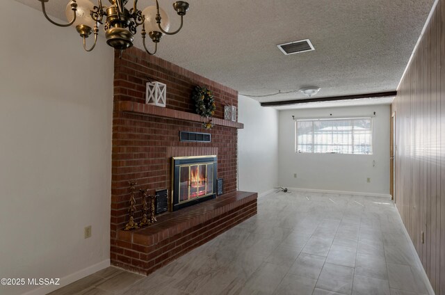 living area featuring visible vents, baseboards, a textured ceiling, a brick fireplace, and a notable chandelier