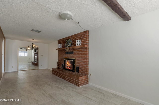 unfurnished living room with a chandelier, a fireplace, a textured ceiling, and baseboards