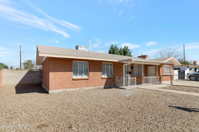 single story home with brick siding, fence, a chimney, and roof with shingles