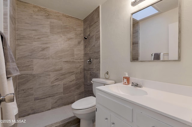 full bathroom featuring tiled shower, vanity, and toilet