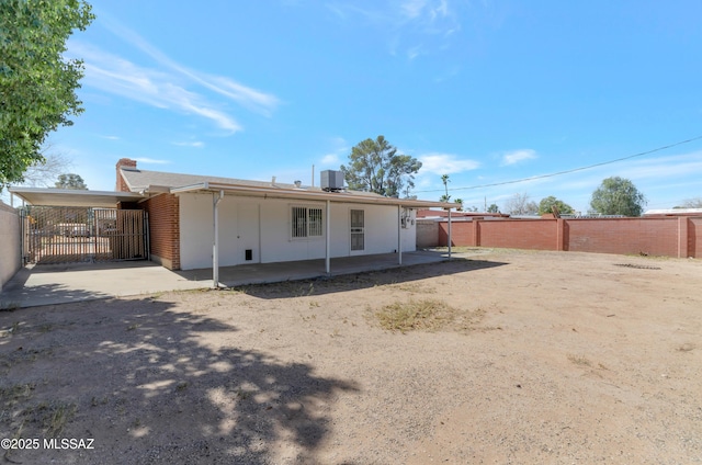 rear view of property featuring an attached carport, cooling unit, and fence