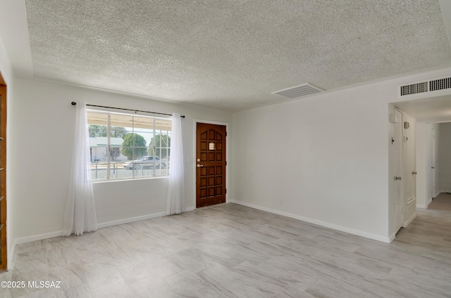 spare room with a textured ceiling, visible vents, and baseboards