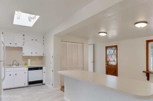 kitchen with light countertops, decorative backsplash, white cabinets, a sink, and dishwasher