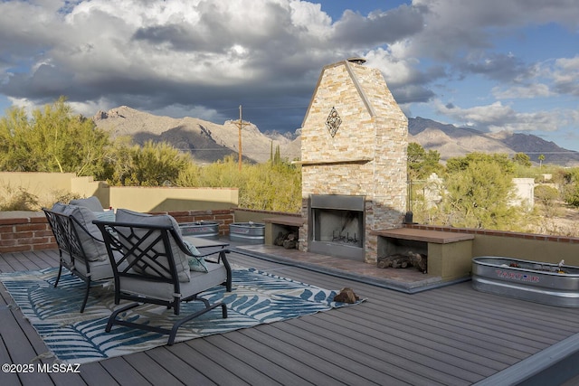 deck featuring an outdoor living space with a fireplace and a mountain view