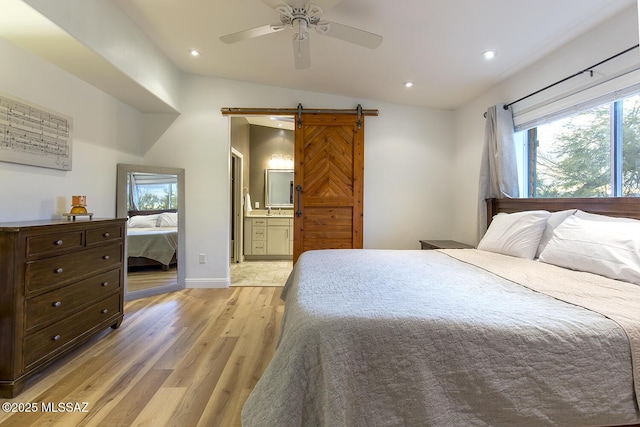 bedroom with baseboards, light wood finished floors, ensuite bath, recessed lighting, and a barn door