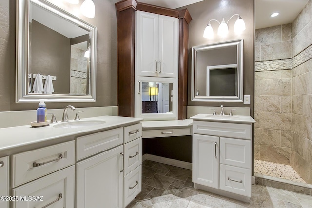 full bath with a sink, stone finish floor, two vanities, and a walk in shower