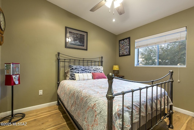 bedroom featuring light wood finished floors, a ceiling fan, baseboards, and vaulted ceiling
