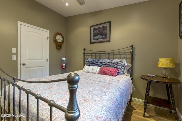bedroom with a ceiling fan, wood finished floors, and baseboards