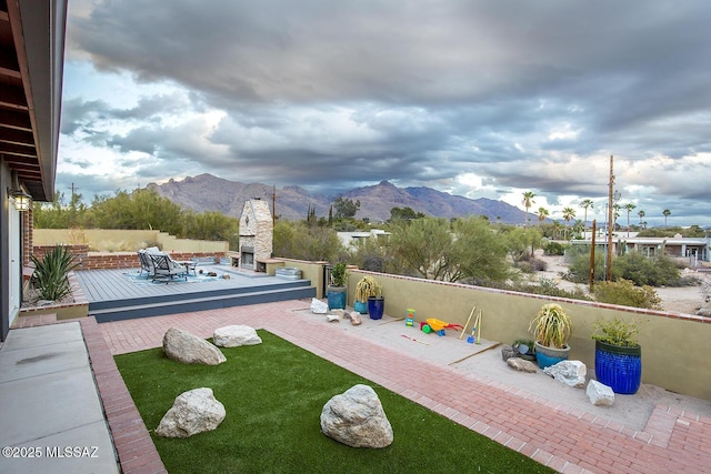 view of yard with a patio, a deck with mountain view, and an outdoor fireplace