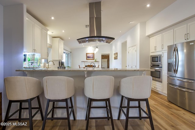kitchen with white cabinetry, a peninsula, island exhaust hood, and stainless steel appliances