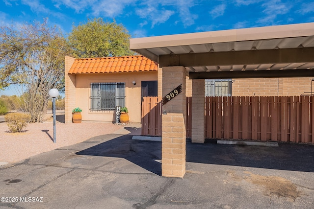 view of front of property featuring a tile roof, fence, and stucco siding