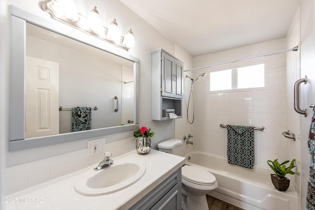 full bathroom featuring tiled shower / bath, vanity, and toilet