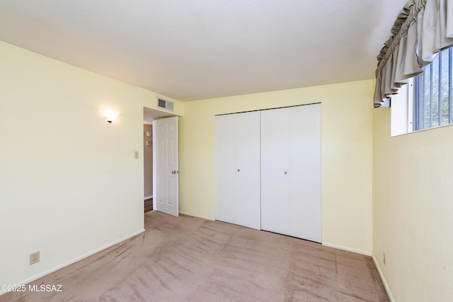 unfurnished bedroom featuring light carpet and a closet