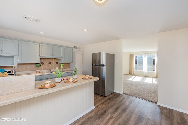 kitchen featuring dark hardwood / wood-style floors, stainless steel refrigerator, tasteful backsplash, sink, and gray cabinetry