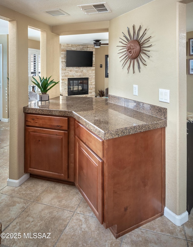 kitchen with light tile patterned flooring, a stone fireplace, and a textured ceiling