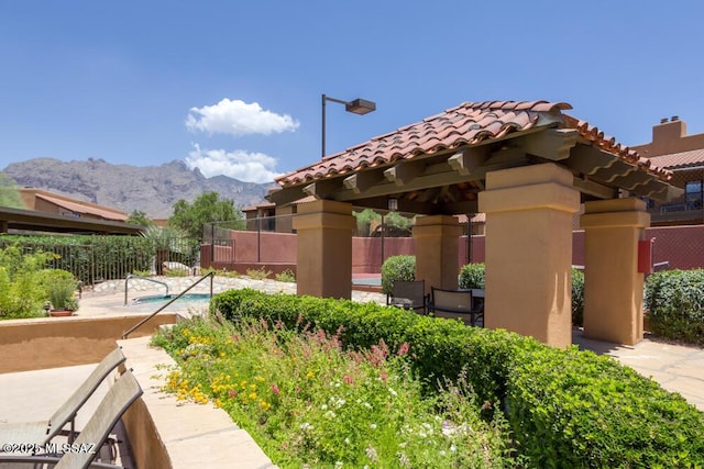 view of property's community featuring a pool, a gazebo, a mountain view, and a patio area