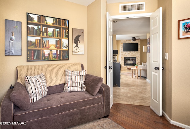 living room with hardwood / wood-style floors and a stone fireplace