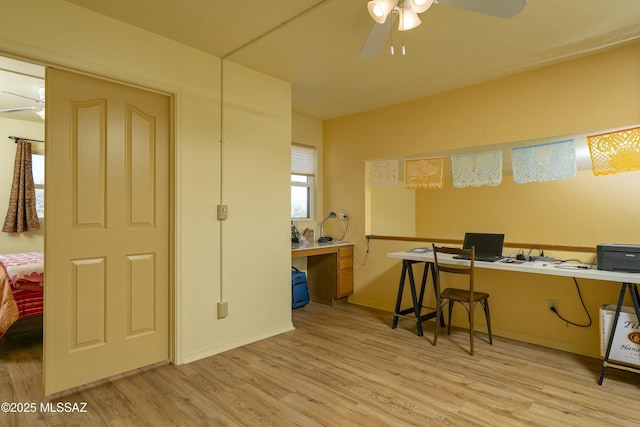 office area with light wood-type flooring, a ceiling fan, and baseboards