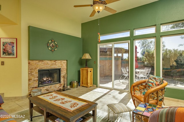 living room with ceiling fan, a fireplace, baseboards, and light tile patterned flooring