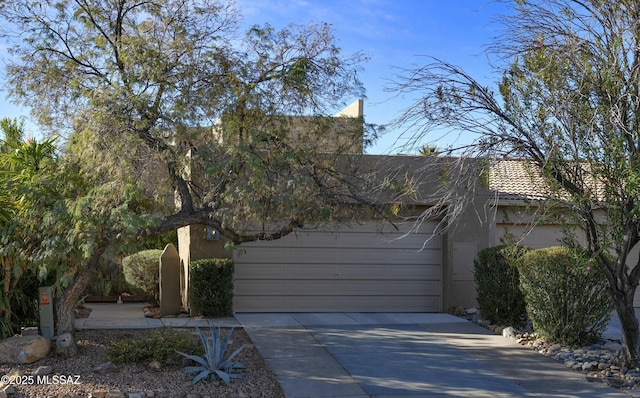 view of side of property with driveway, a tile roof, an attached garage, and stucco siding