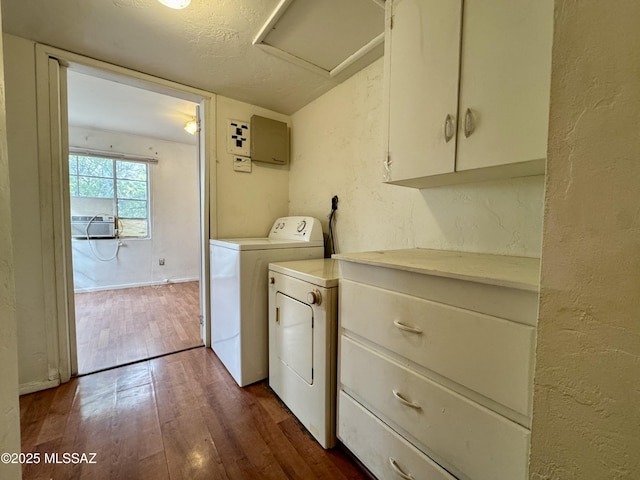 laundry area featuring cabinet space, a textured wall, dark wood-type flooring, attic access, and washer and dryer