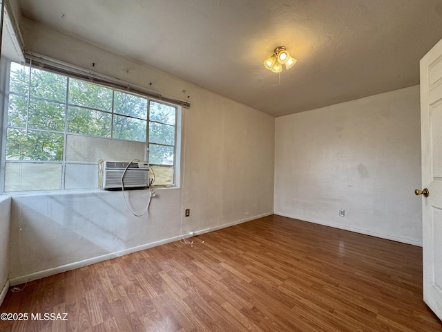 spare room with cooling unit, wood finished floors, and baseboards