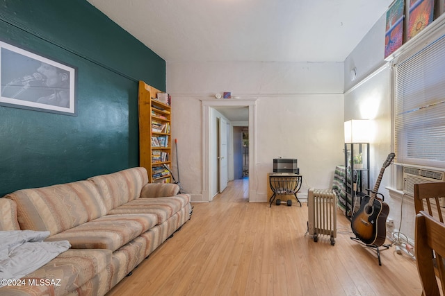 living area featuring cooling unit, radiator heating unit, and wood finished floors