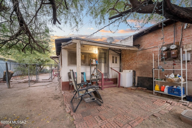 patio terrace at dusk featuring washer / clothes dryer, fence, and a gate