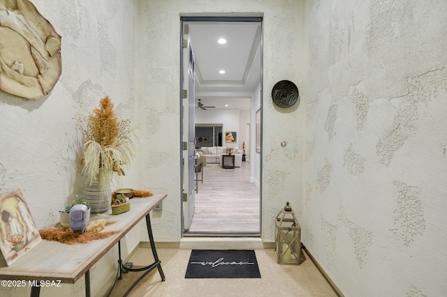 doorway to outside featuring baseboards, a tray ceiling, and recessed lighting