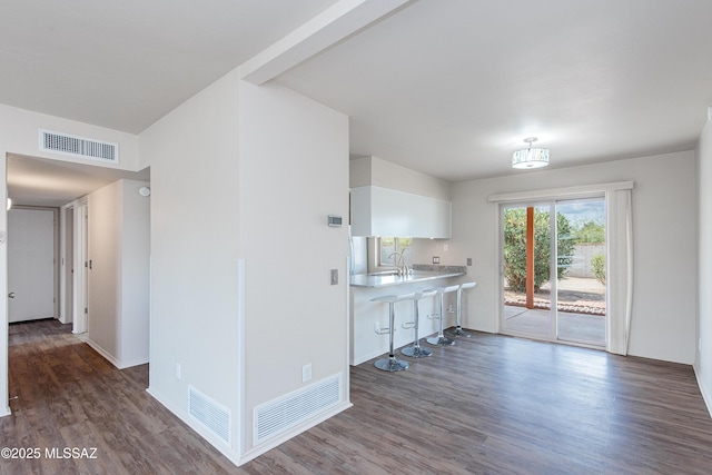 interior space with visible vents, baseboards, wood finished floors, and light countertops