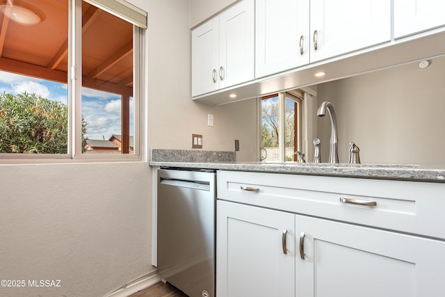 kitchen featuring a sink, light stone counters, dishwasher, and white cabinetry