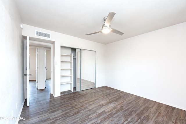 unfurnished bedroom with dark wood-style floors, visible vents, a ceiling fan, and a closet