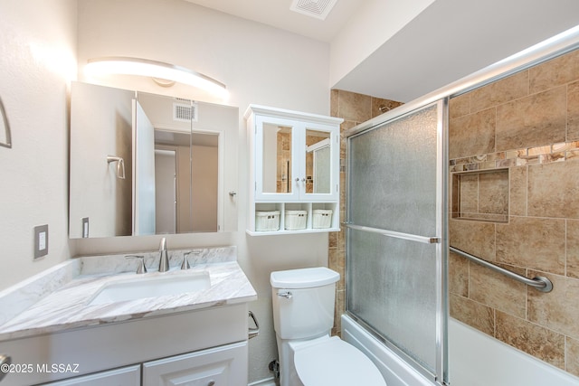 full bathroom with visible vents, shower / bath combination with glass door, vanity, and toilet