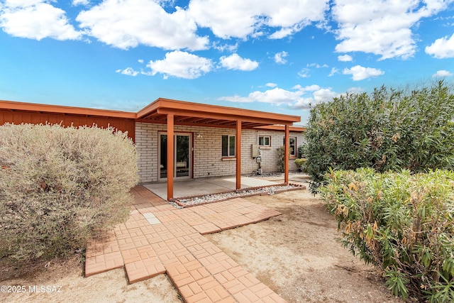 back of property featuring a patio and brick siding