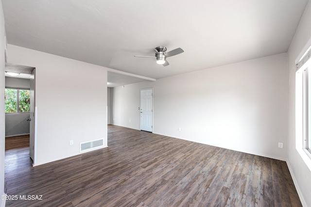empty room featuring visible vents, dark wood-type flooring, and a ceiling fan