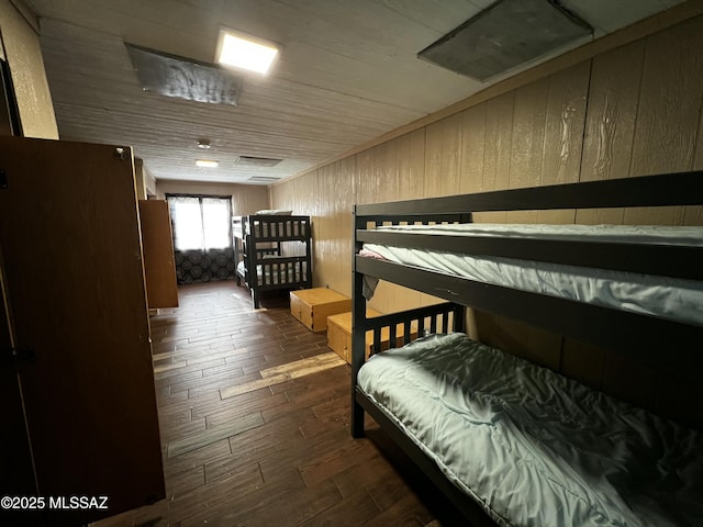 bedroom with dark wood-style floors, wood ceiling, and wooden walls