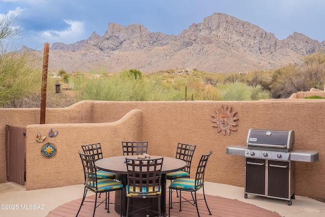 exterior space with a deck with mountain view, outdoor dining area, and area for grilling