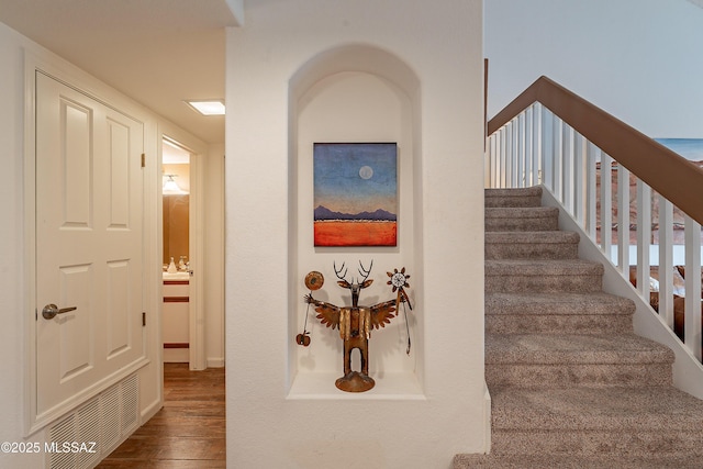 staircase with visible vents and wood finished floors