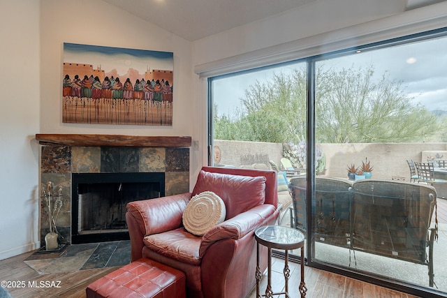 living area with a fireplace, baseboards, wood finished floors, and lofted ceiling