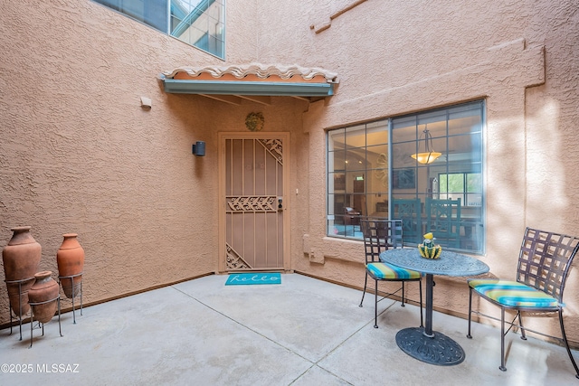 view of exterior entry with a tiled roof, a patio, and stucco siding