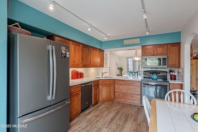 kitchen with appliances with stainless steel finishes, brown cabinetry, and light wood-style flooring