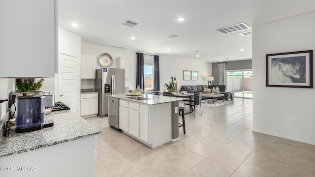 kitchen featuring a kitchen island, a breakfast bar, white cabinets, stainless steel refrigerator with ice dispenser, and light stone countertops