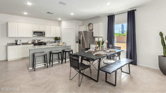 dining area featuring sink and light tile patterned flooring