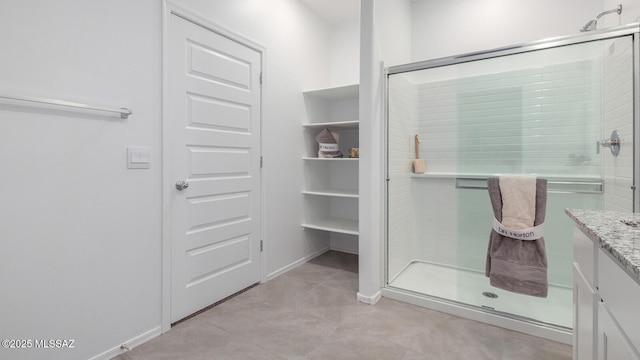 bathroom featuring vanity, a shower with shower door, and tile patterned flooring