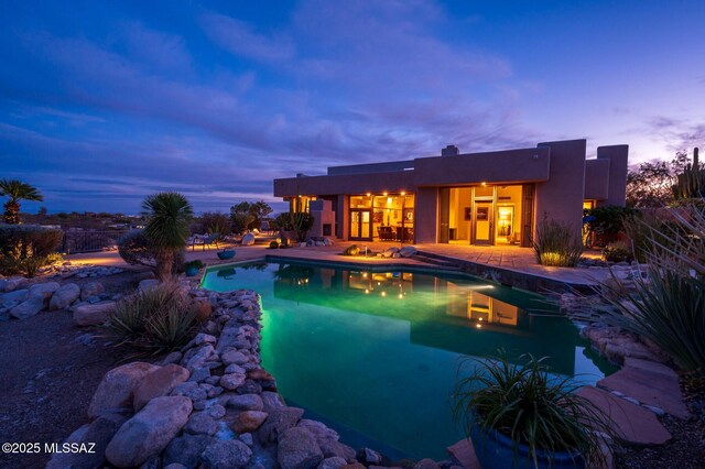 back house at dusk featuring a mountain view and a patio